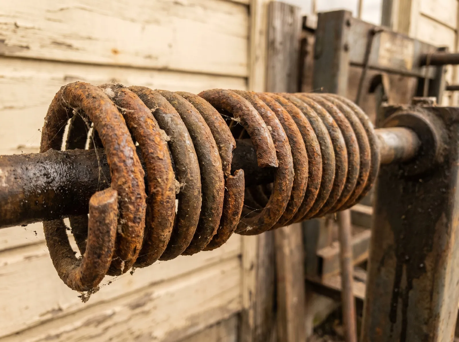 A rusted coil spring, parted between its coils, on old equipment